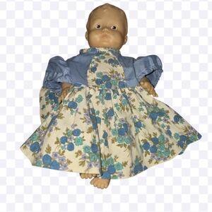 Vintage baby doll with molded plastic head, arms, and legs, dressed in a blue